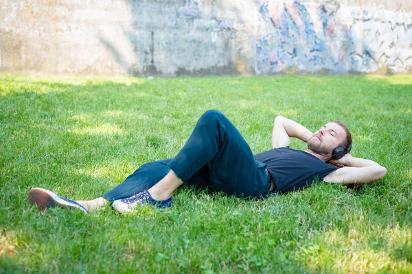 Hipster modern snygg blond man lyssnar musik i parken — Stockfoto