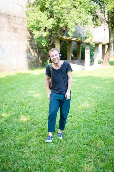 Hipster modern stylish blonde man listening music in park — Stock Photo, Image