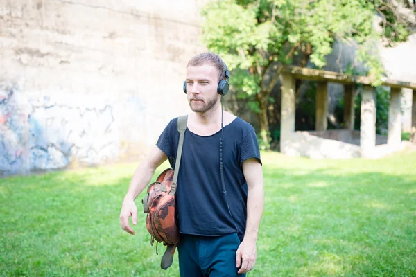 Hipster modern snygg blond man lyssnar musik i parken — Stockfoto