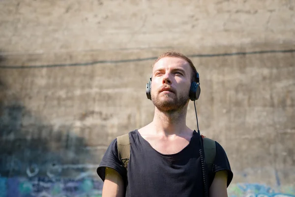 Hipster modern stylish blonde man listening music in park — Stock Photo, Image