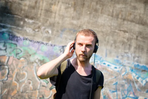 Hipster modern snygg blond man lyssnar musik i parken — Stockfoto