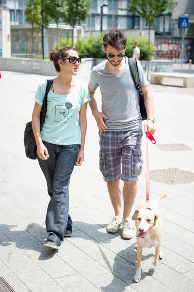 Пара с собакой гуляет по улице — стоковое фото