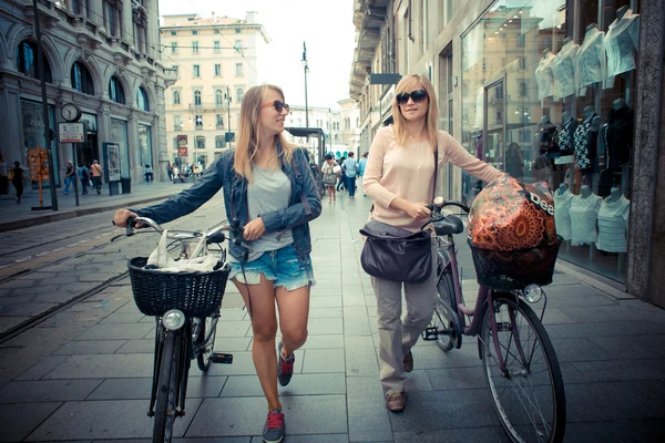 Zwei schöne blonde Frauen auf dem Fahrrad einkaufen — Stockfoto