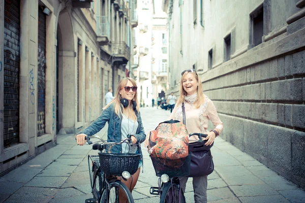 Two beautiful blonde women shopping on bike — Stock Photo, Image