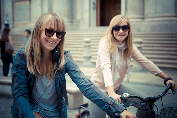 Two beautiful blonde women shopping on bike — Stock Photo, Image