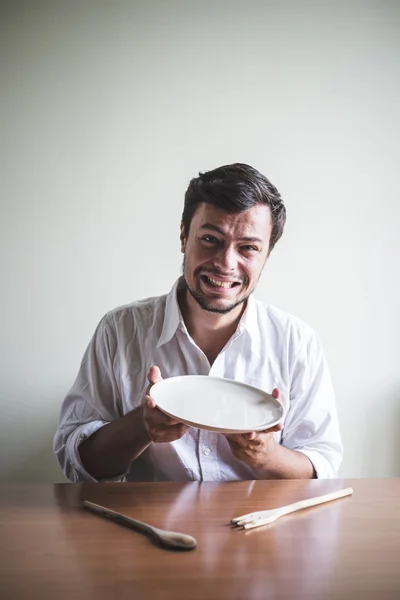 Joven elegante hombre con camisa blanca comiendo en las comidas — Foto de Stock