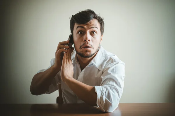 Ung snygg man med vit skjorta på telefonen — Stockfoto