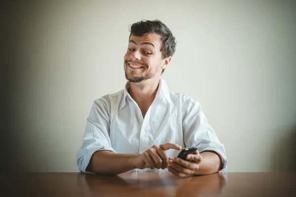 Молодой стильный мужчина в белой рубашке на телефоне — стоковое фото