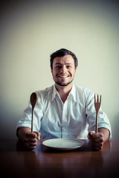 Молодой стильный мужчина в белой рубашке ест во время еды — стоковое фото