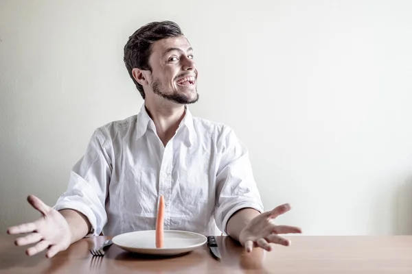 Молодой стильный мужчина в белой рубашке, поедающий морковь — стоковое фото