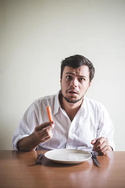 Jovem homem elegante com camisa branca comendo cenoura — Fotografia de Stock