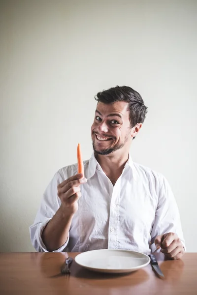 Jovem homem elegante com camisa branca comendo cenoura — Fotografia de Stock