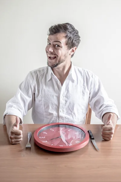 Jonge stijlvolle man met wit overhemd eten rode klok — Stockfoto