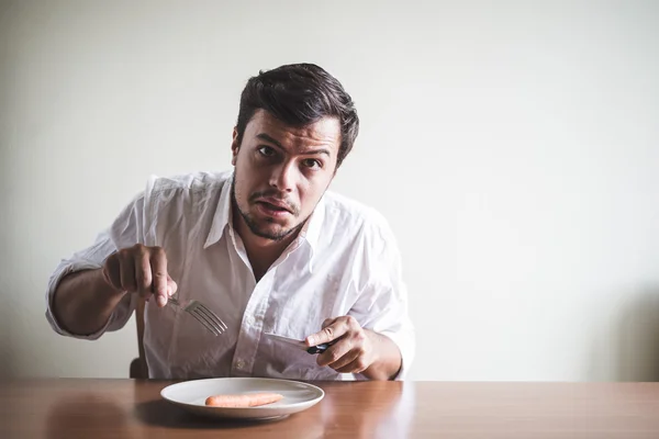 Jeune homme élégant avec chemise blanche manger carotte — Photo