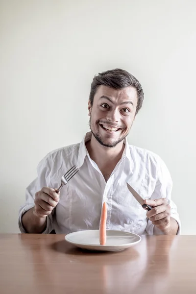 Stilvoller junger Mann mit weißem Hemd, der Möhren isst — Stockfoto