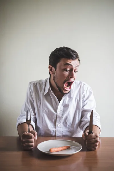 Stijlvolle jongeman met wit overhemd eten wortel — Stockfoto