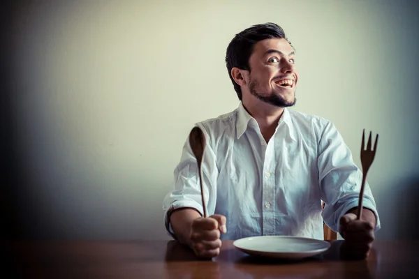 Молодой стильный мужчина в белой рубашке ест во время еды — стоковое фото