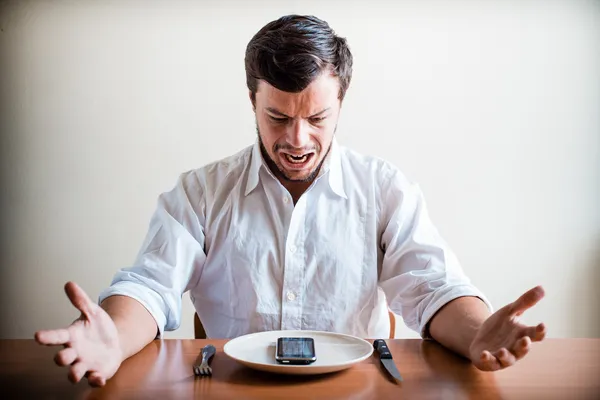 Hombre joven y elegante con camisa blanca y teléfono en el plato — Foto de Stock