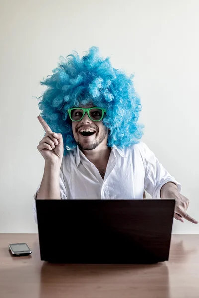 Engraçado louco jovem com peruca azul usando notebook — Fotografia de Stock