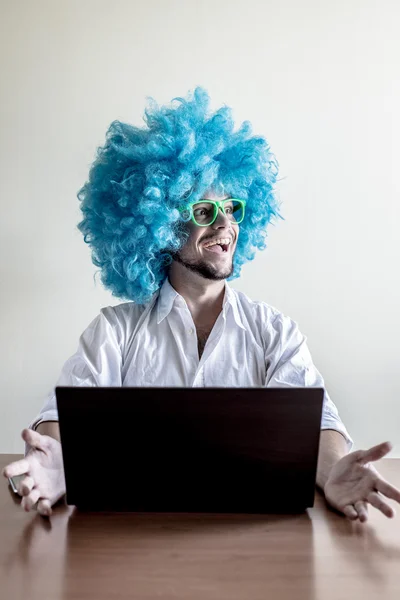 Engraçado louco jovem com peruca azul usando notebook — Fotografia de Stock