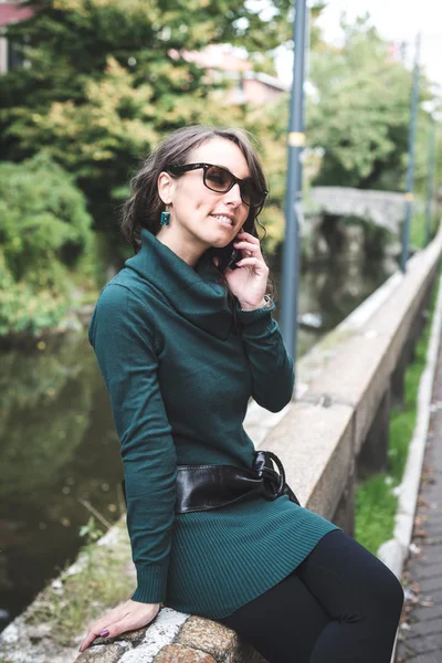 Belle femme avec col roulé au téléphone dans la ville — Photo