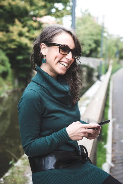 Bella donna con dolcevita al telefono in città — Foto Stock