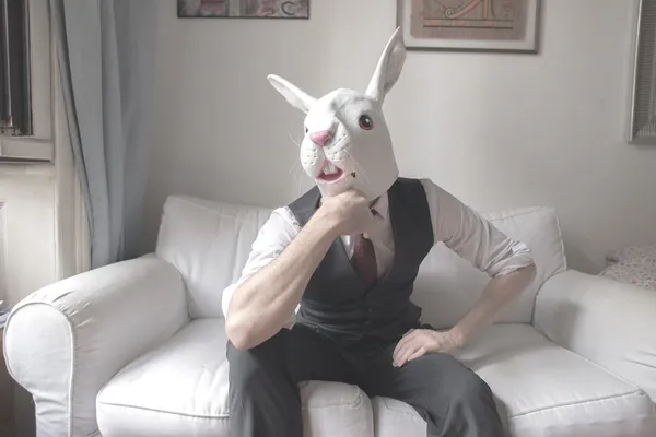 坐在沙发上的兔面具男人 — 图库照片