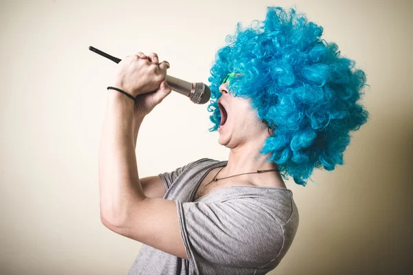 Cara engraçado com peruca azul cantando — Fotografia de Stock