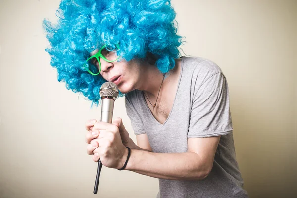 Zábavný chlapík s modrou paruku zpěv — Stock fotografie