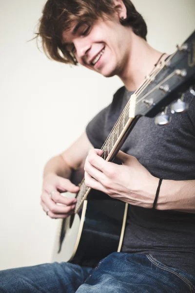 Elegante joven rubia hipster hombre tocando la guitarra — Foto de Stock