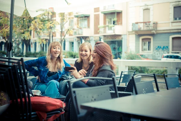 Three friends woman at the bar using phone — Stock Photo, Image