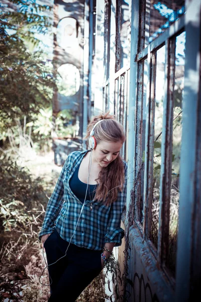 Beautiful young blonde hipster woman listening music — Stock Photo, Image