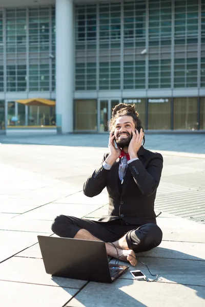 Стильный элегантный дреды бизнесмен слушает музыку — стоковое фото