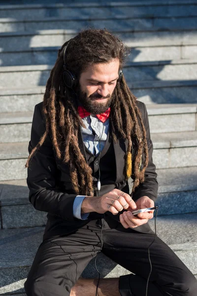 スタイリッシュなエレガントなドレッドヘアのビジネスマンは音楽を聴く — ストック写真