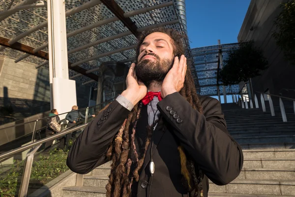 Стильный элегантный дреды бизнесмен слушает музыку — стоковое фото