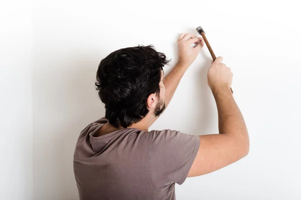 Joven hombre bricolaje martilleo clavo pared — Foto de Stock