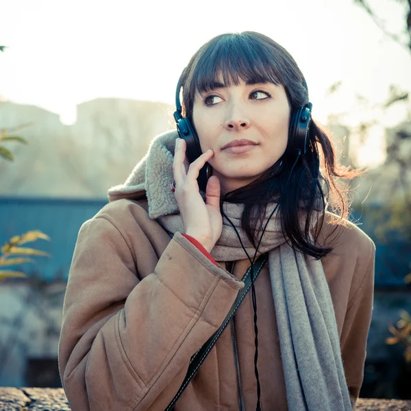 Vacker ung kvinna som lyssnar på musik hörlurar — Stockfoto