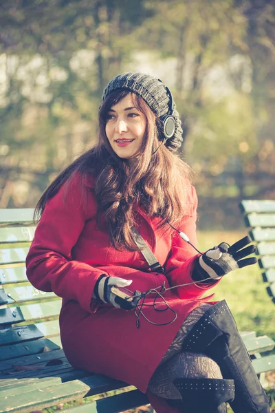 Beautiful woman red coat listening music — Stock Photo, Image