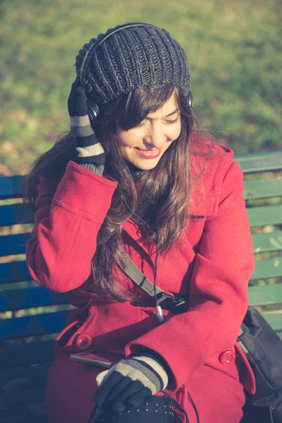 Belle femme manteau rouge écouter de la musique — Photo