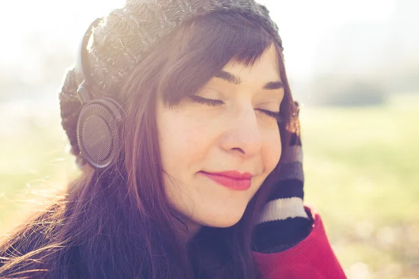 Hermosa mujer rojo abrigo escuchar música — Foto de Stock