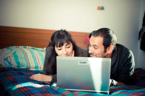 Casal apaixonado na cama usando notebook — Fotografia de Stock