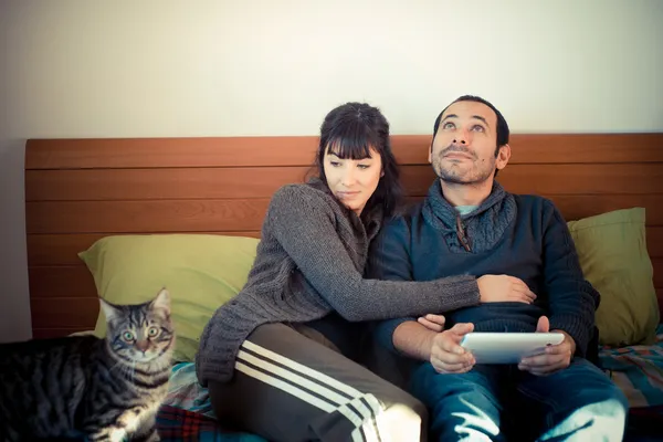 Par forelsket på sengen ved hjælp af tablet - Stock-foto
