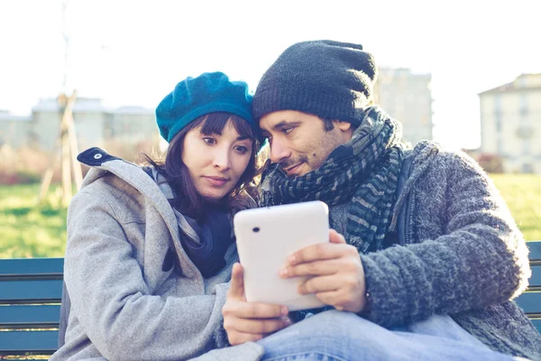 Paar in liefde met behulp van Tablet PC in het park — Stockfoto