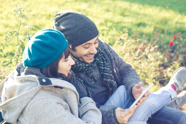 Pareja enamorada usando tableta en el parque — Foto de Stock