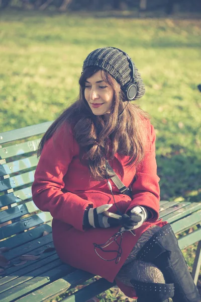 Mooie vrouw rode jas luisteren muziek — Stockfoto