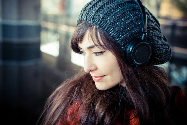 Mooie vrouw rode jas luisteren muziek — Stockfoto