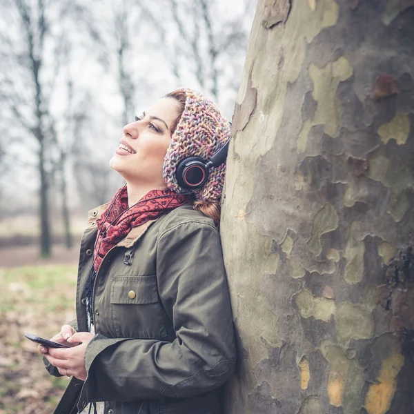 Schöne brünette Frau hört Musik mit Kopfhörern — Stockfoto