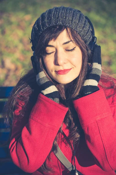 Krásná žena červený kabát poslech hudby — Stock fotografie