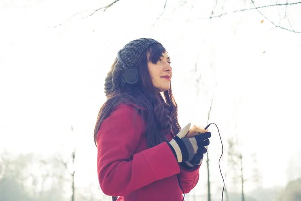 Piękna kobieta czerwony płaszcz słuchania muzyki — Zdjęcie stockowe