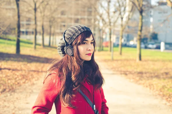 美しい女性の赤いコート音楽を聴く — ストック写真